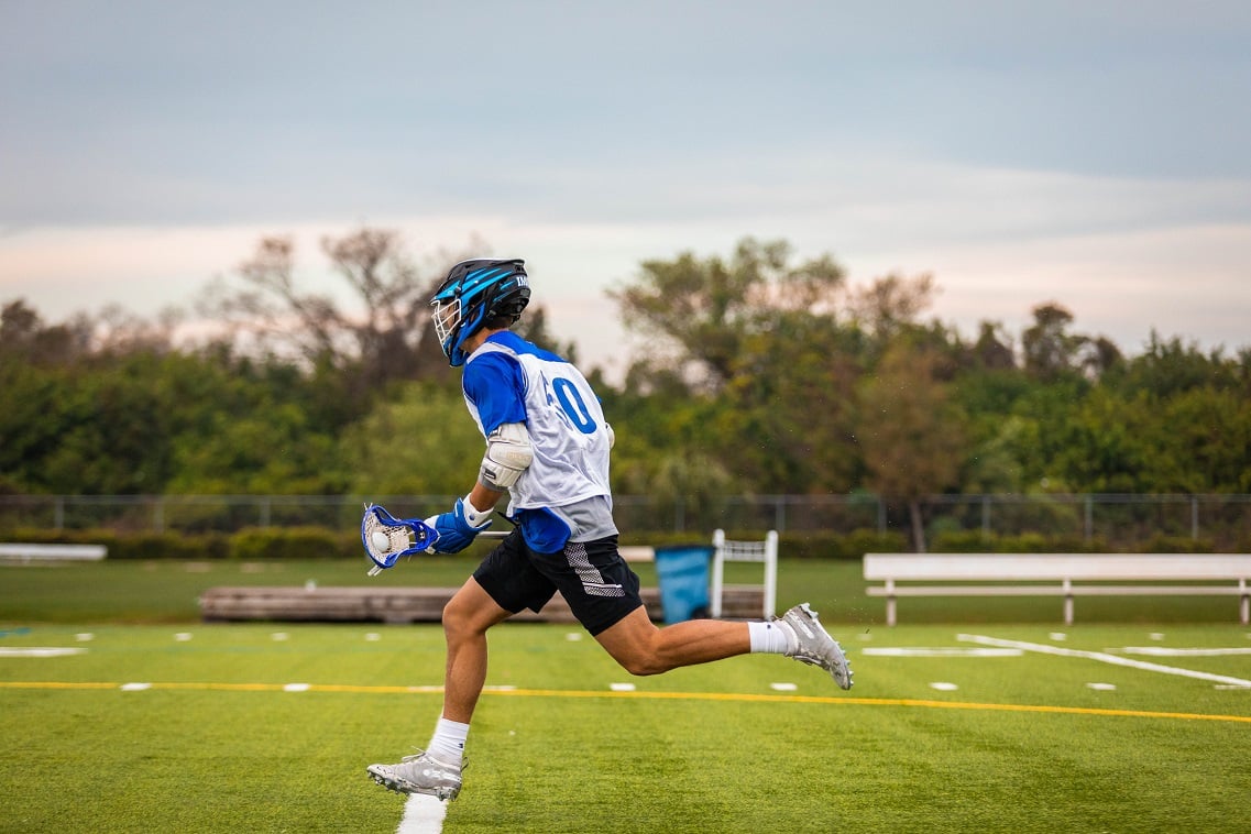 Lacrosse player runs on lacrosse field | IMG Academy